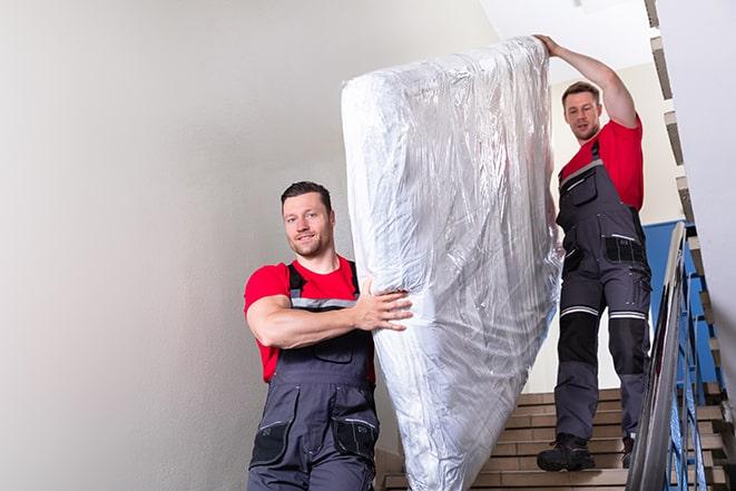 two people carrying a box spring down a staircase in New Britain, CT